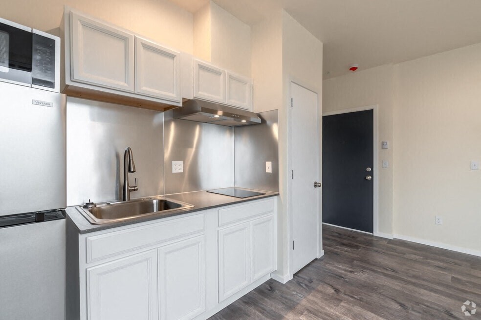 an empty kitchen with white cabinets and a stainless steel sink