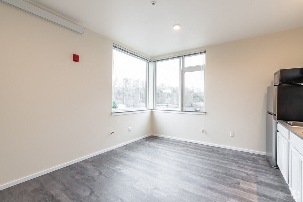 an empty living room with a large window and a kitchen