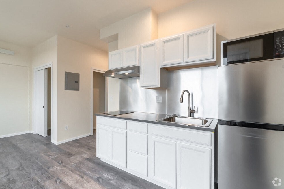an empty kitchen with white cabinets and stainless steel appliances