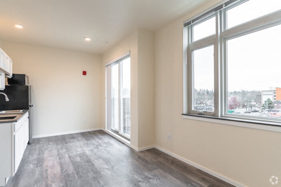 an empty living room with large windows and a kitchen