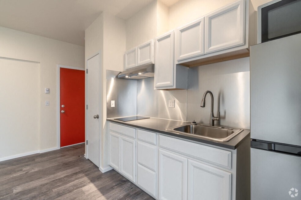 a kitchen with white cabinets and a sink and a red door