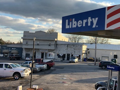 a sign in front of a grocery store with cars parked