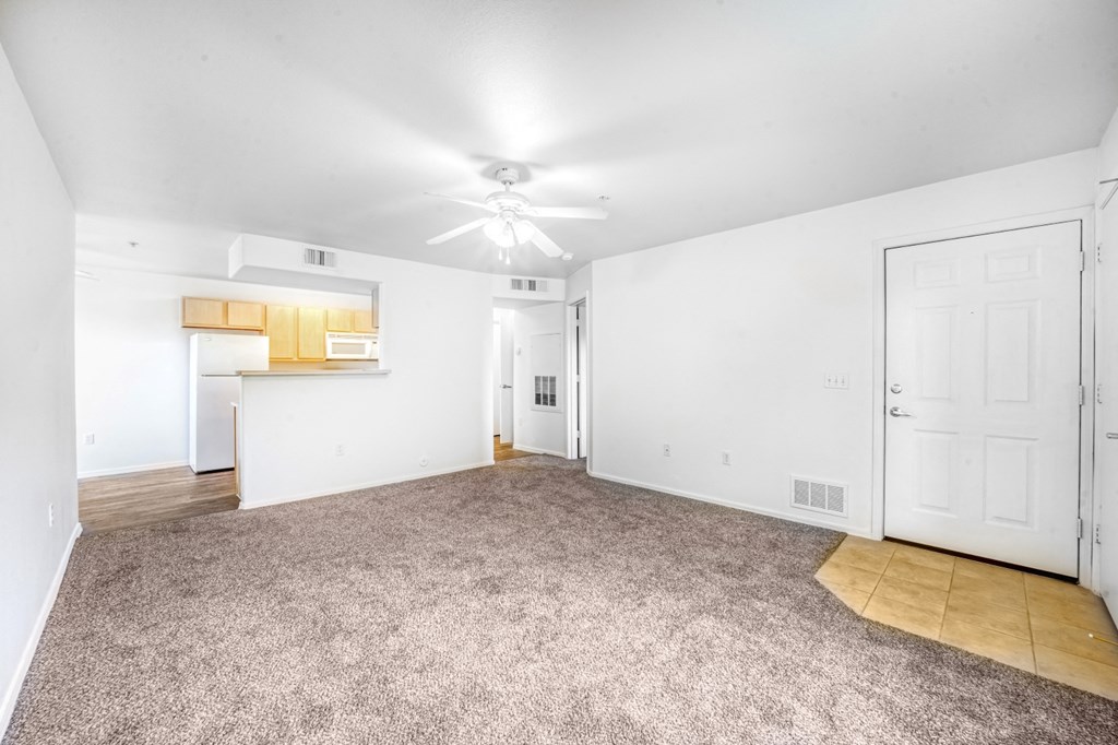 an empty living room with white walls and a ceiling fan