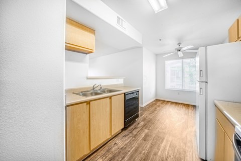 a kitchen with wood flooring and white walls and a stainless steel sink and refrigerator