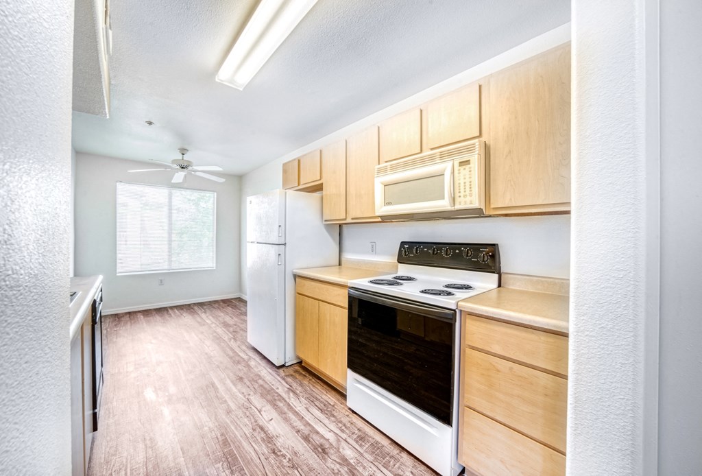 an empty kitchen with wooden cabinets and white appliances