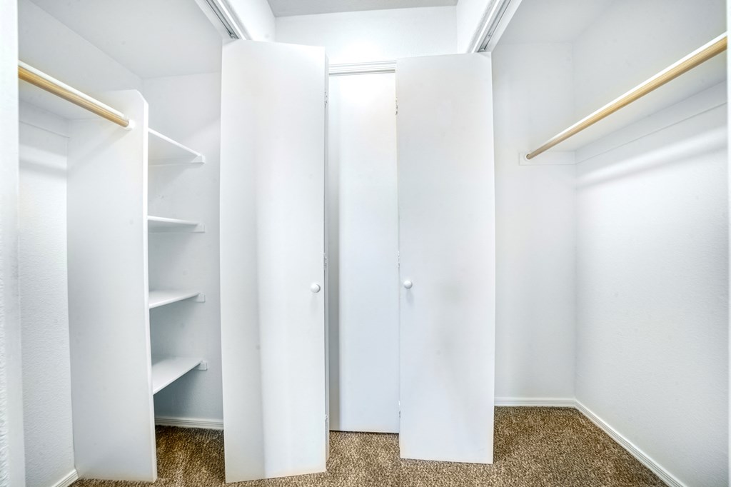 a walk in closet with white closets and white walls