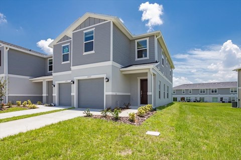 a gray house with a lawn in front of it