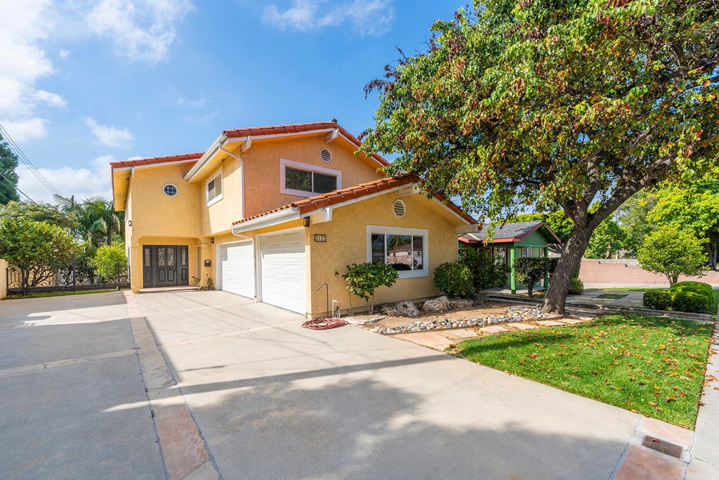 A yellow house with a red roof and a white garage door.