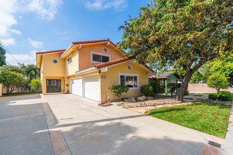 A yellow house with a red roof and a white garage door.
