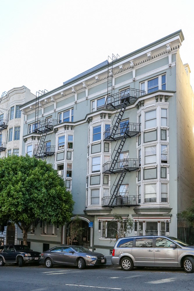 a tall building with cars parked in front of it