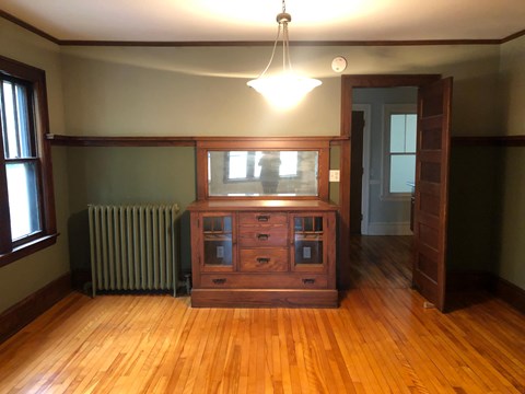 an empty living room with a dresser and a window