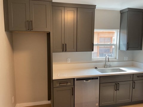 a kitchen with gray cabinets and a sink and a window