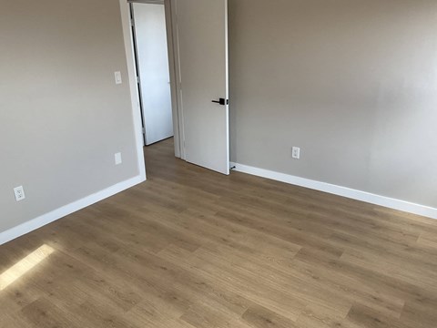 a living room with wood flooring and white walls and a door