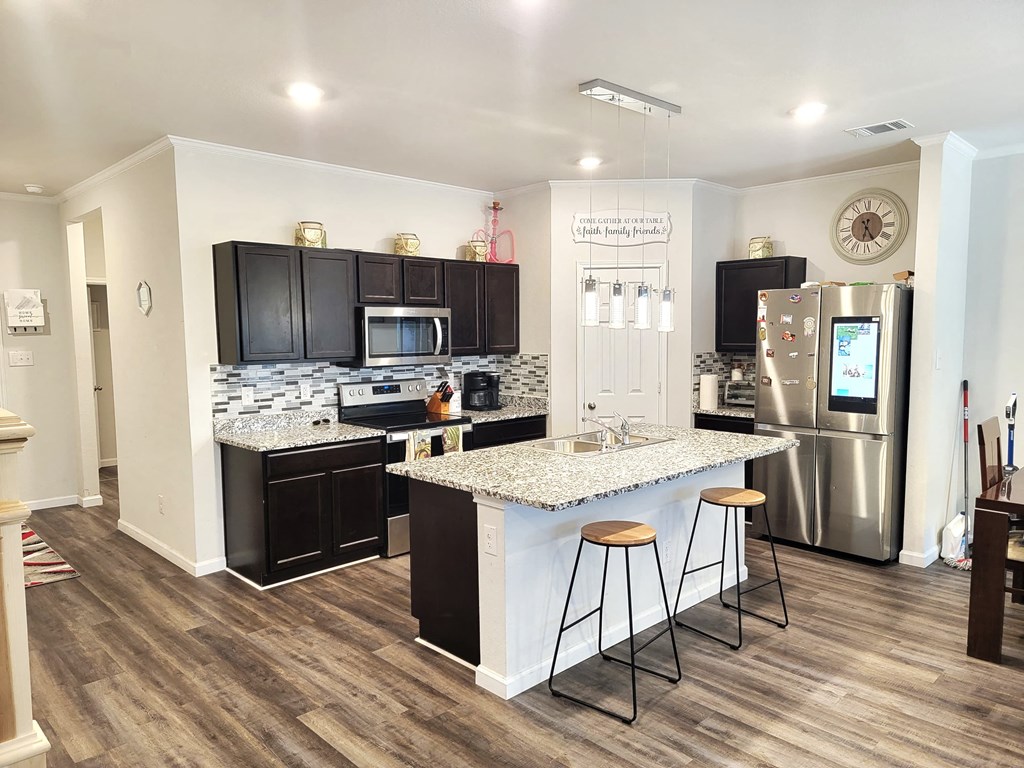 a kitchen with an island and stainless steel refrigerator
