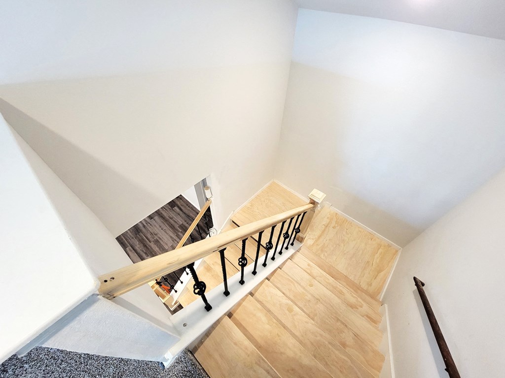 a stairwell with wooden stairs and wooden floors and white walls