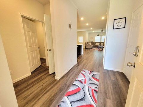 a renovated living room and hallway with wood flooring and a rug