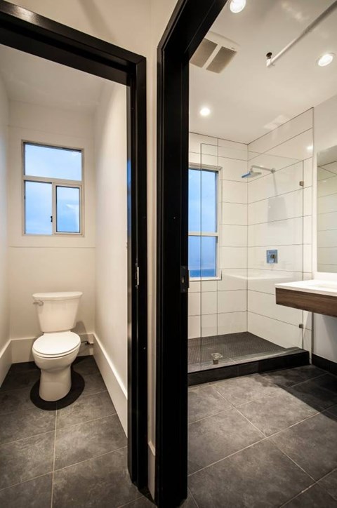 A bathroom with a toilet, a walk-in shower, and a window.