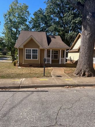 a house on the side of a street with a tree