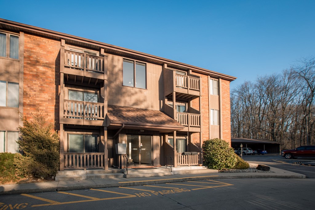 A large apartment building with a parking lot in front.
