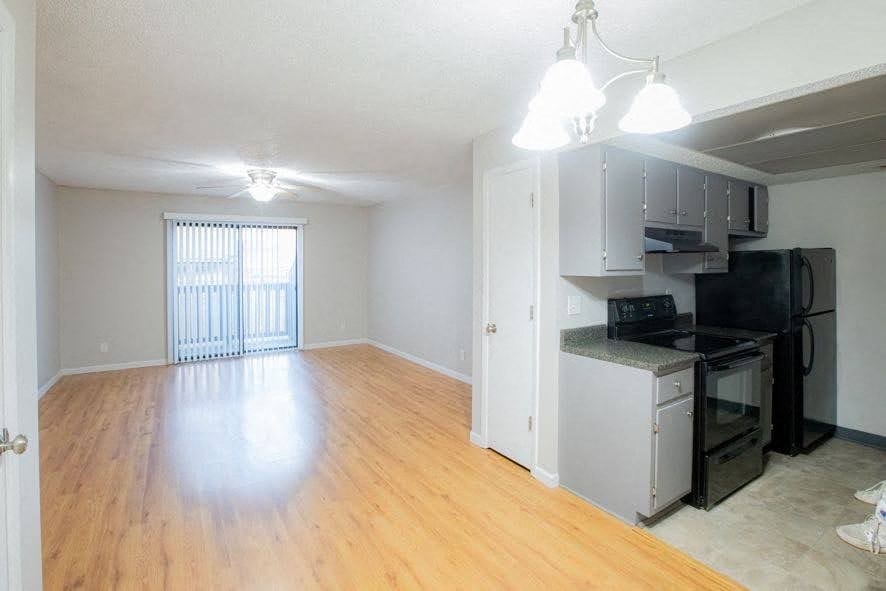 A kitchen area with a black fridge and white cabinets.
