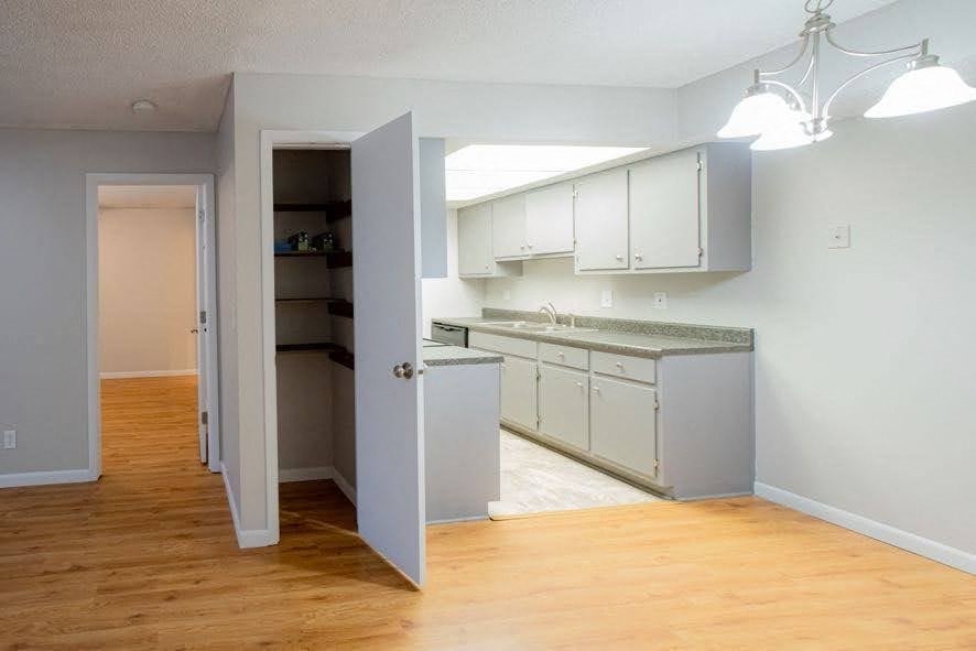 A kitchen with a white cabinetry and a wooden floor.