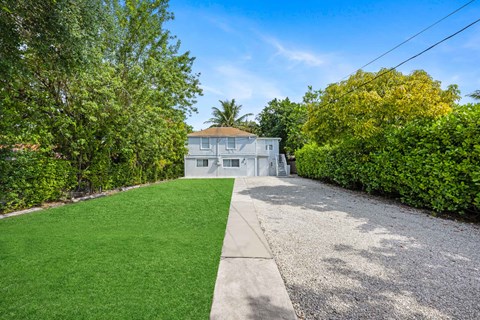 A house with a green lawn and trees in the background.
