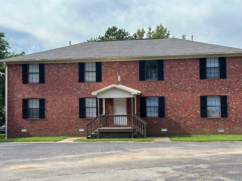 the front of a red brick building with a porch