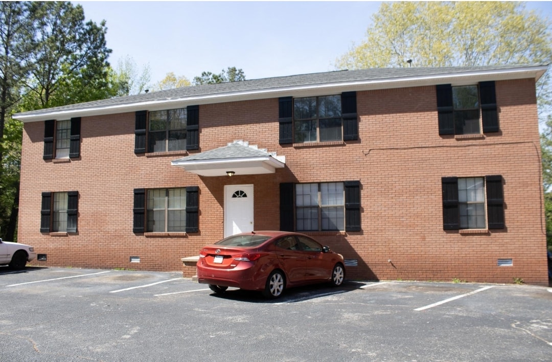 a red car parked in front of a brick building