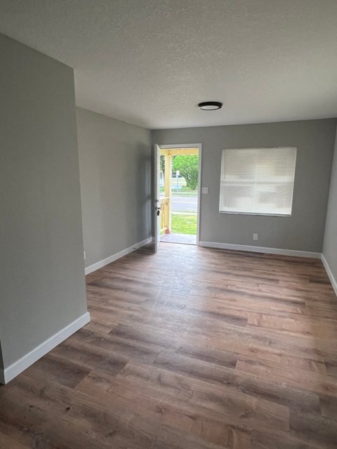 an empty living room with wooden floors and grey walls