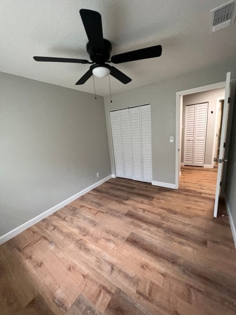 a living room with wood floors and a ceiling fan