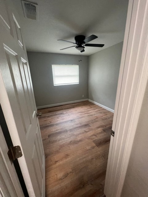 a empty room with wood floors and a ceiling fan