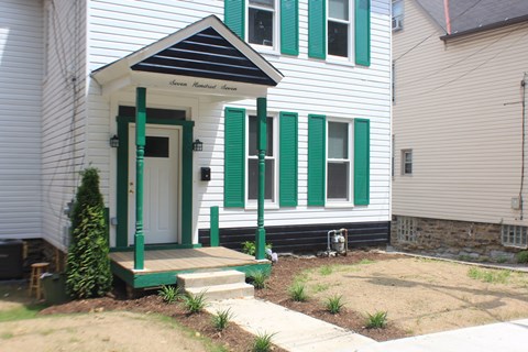 A white house with green shutters and a green door.