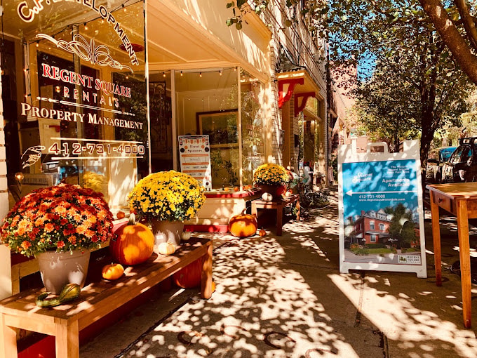 A flower shop with a sign that says Regent Square Rentals Property Management.