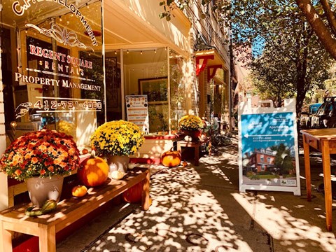 A flower shop with a sign that says Regent Square Rentals Property Management.