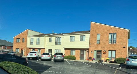 A parking lot in front of a two-story building with cars parked.