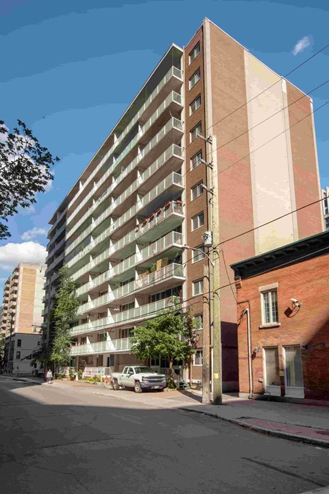 A tall apartment building with balconies on the second floor.
