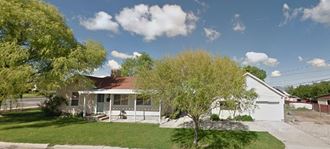 a small white house with a lawn and trees