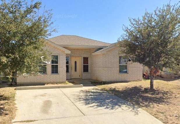 a white brick house with a tree and a sidewalk