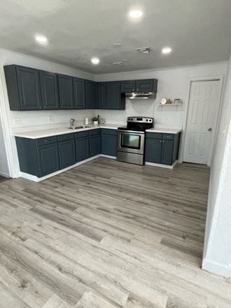 a kitchen with dark cabinets and a wooden floor