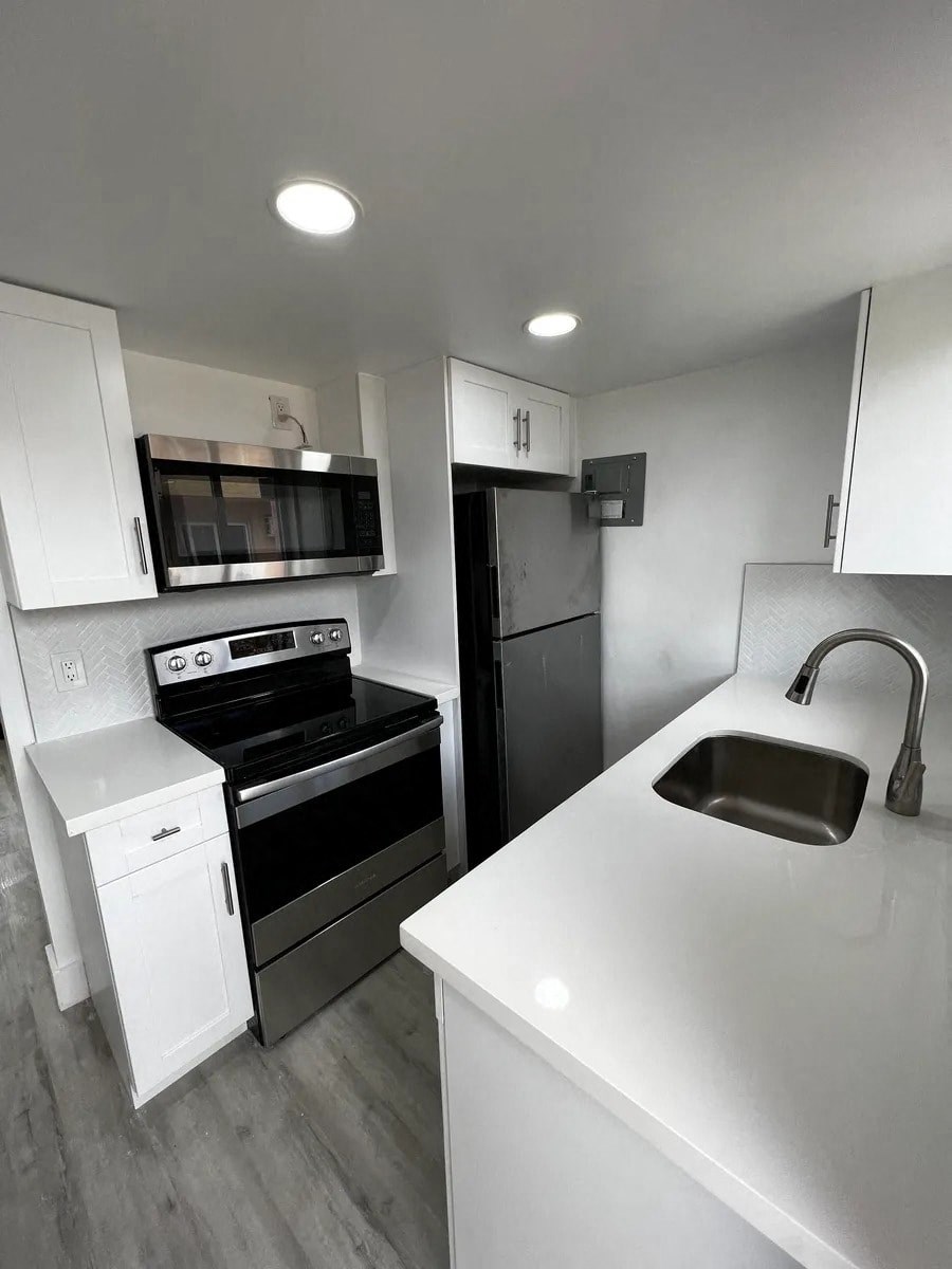 A modern kitchen with white countertops and stainless steel appliances.