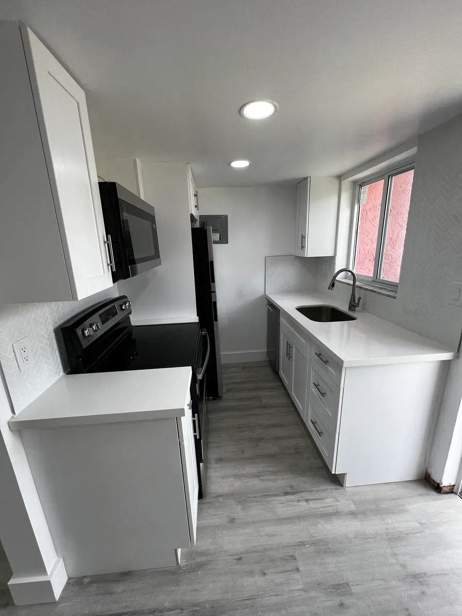 A kitchen with white cabinets and a black stove top oven.