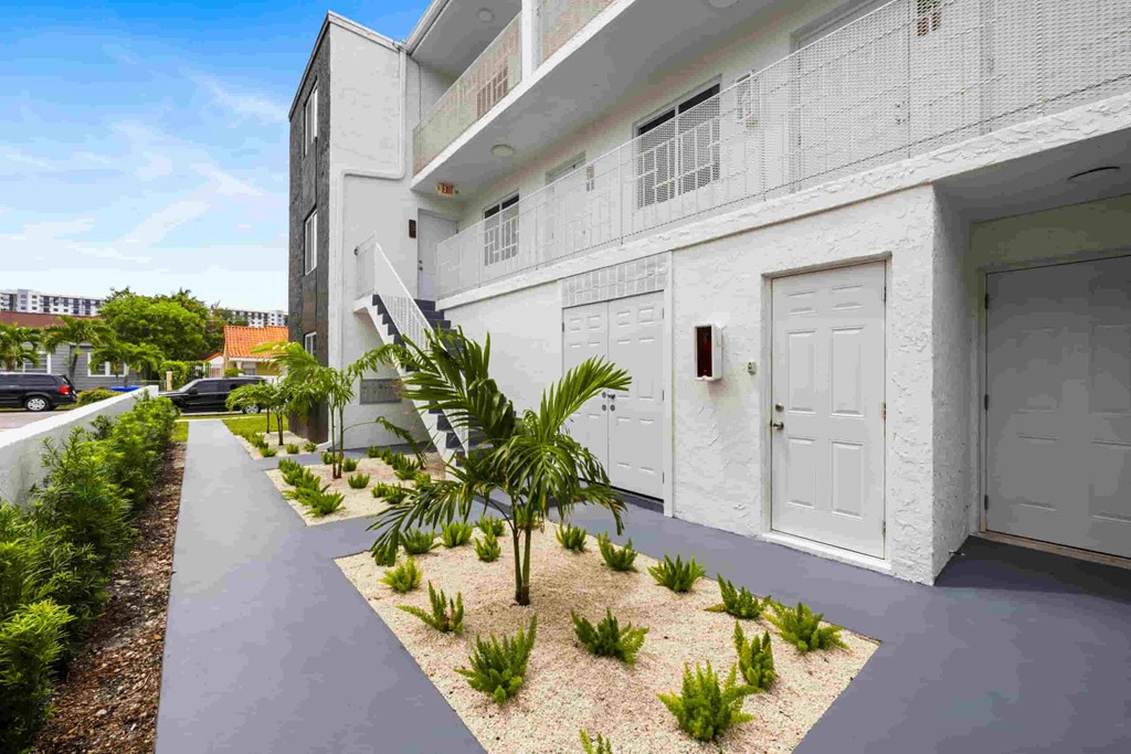 A white building with a small garden in front.