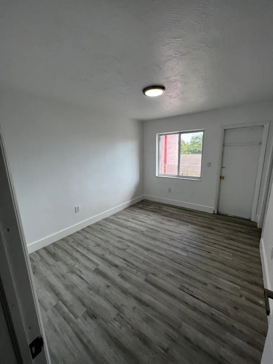 A room with wooden flooring and a window with red curtains.