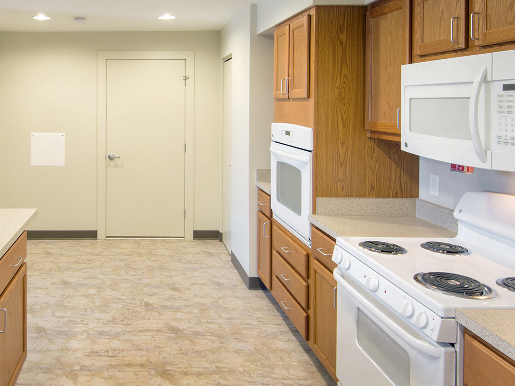 an empty kitchen with white appliances and wooden cabinets