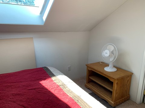 a small bedroom with a bed and a fan