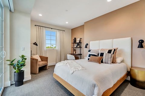A bedroom with a large bed and a window with curtains.