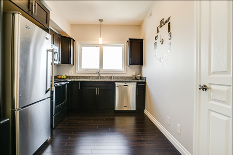 A kitchen with a stainless steel refrigerator and black cabinets.