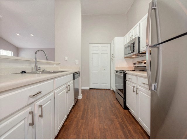 a large kitchen with white cabinets and stainless steel appliances