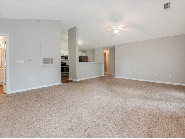 an empty living room with carpet and a ceiling fan