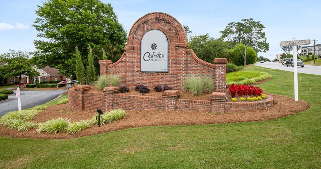 a brick monument with a sign in front of a garden